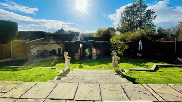 A backyard with a stone patio, a wooden fence, and a house in the background. - Ivy's End (Loughborough)