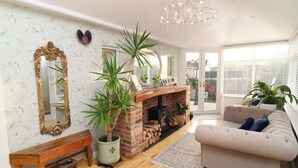 A cozy living room with a fireplace, a sofa, a wooden bench, and a large mirror. - Ivy's End (Loughborough)