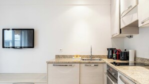 Una cocina moderna con horno empotrado, un lavamanos y una encimera con cafetera y otros electrodomésticos.