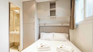 Un dormitorio con cama, armario y baño a la vista a través de una puerta abierta.