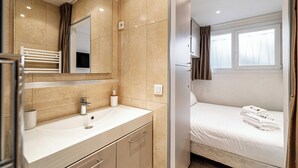 Un baño moderno con lavamanos, espejo y cama con toallas.