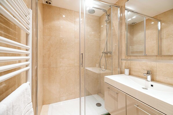 A modern bathroom with a glass-enclosed shower, a white sink, and a large mirror. - Modern Apartment a/c 1br-4p - With Balcony (Cannes)