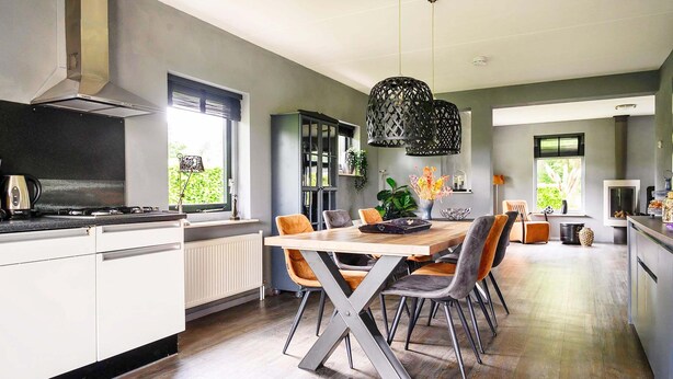 A modern kitchen with a dining area, featuring a large island, grey cabinetry, and a view of the outdoors. - Detached Holiday Home With Jetty and Outdoor spa (Vlagtwedde)