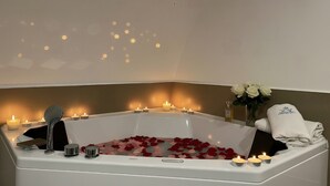 A bathtub with rose petals, candles, and a towel with a logo. - Bed and Breakfast 'Appartamento - Orchidea Celeste' with Sea View, Wi-Fi and Air Conditioning (Manfredonia)