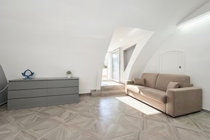 Een moderne loft slaapkamer met een vloer met een geometrisch patroon, een bank, een dressoir en een deur.
