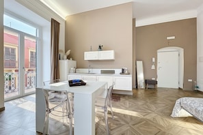 A modern kitchen with white cabinets, a dining table with chairs, and a large window with curtains. - Triple Room 'Orchidea Celeste' with Sea View, Wi-Fi and Air Conditioning (Manfredonia)