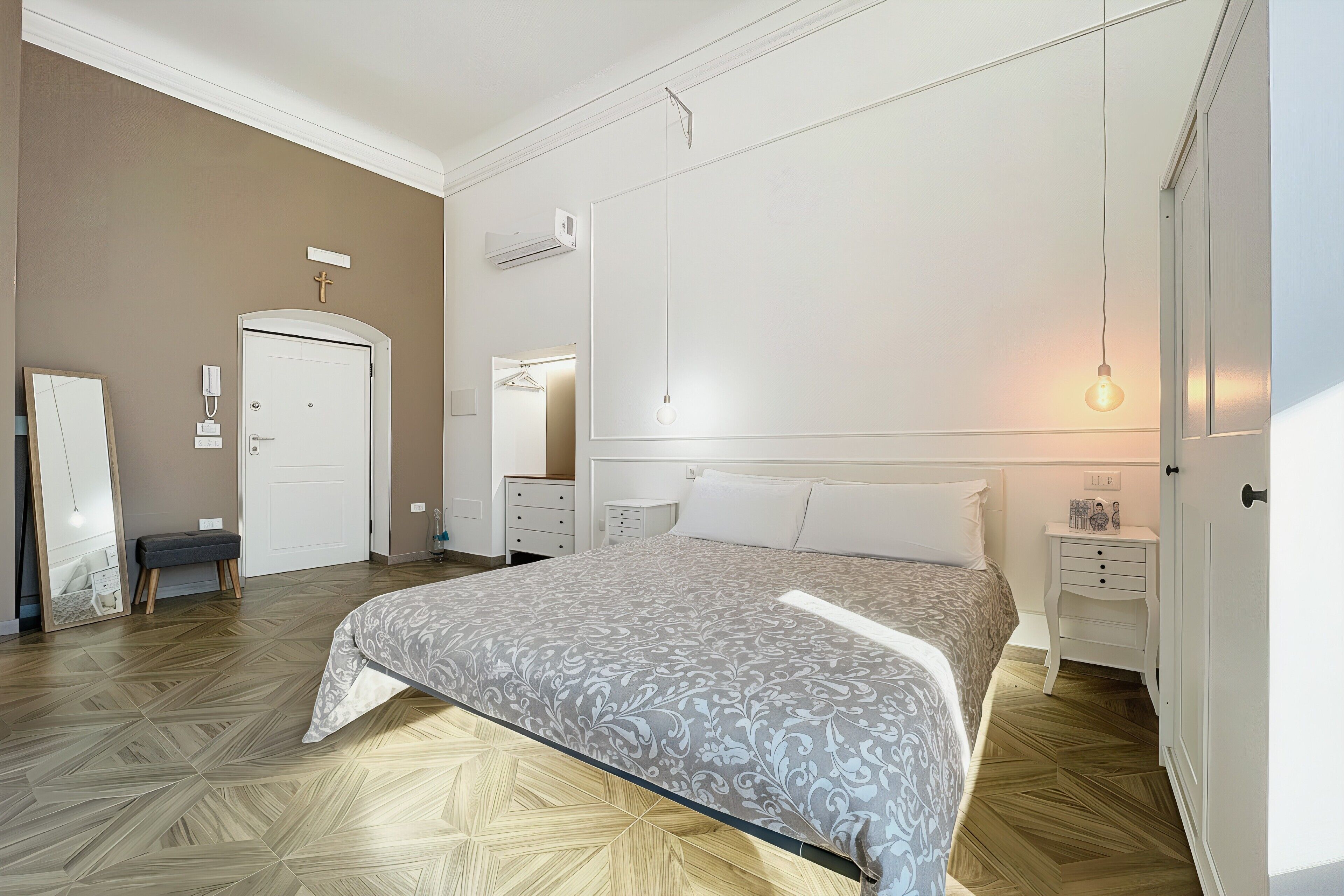 A bedroom with a bed, bedside tables, a wardrobe, a mirror, and a hanging light fixture.