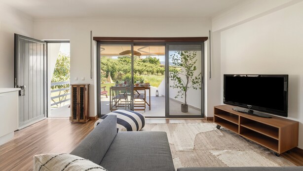 A living room with a sofa, TV, sliding glass door, and a view of the outdoors.