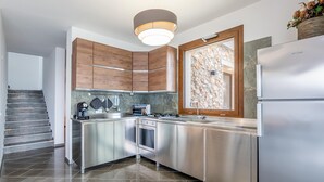 A modern kitchen with stainless steel appliances, wooden cabinets, a stone backsplash, and a built-in oven. - Villa Altamarea - Scopello (Scopello)