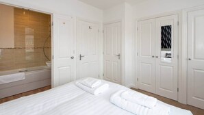Una habitación de hotel con una cama grande, una bañera y puertas blancas.