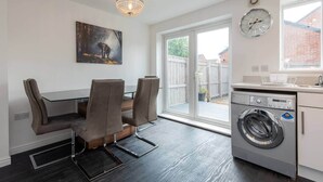 Eine moderne Küche mit Waschmaschine, einem Essbereich mit Stühlen und einem großen Fenster.