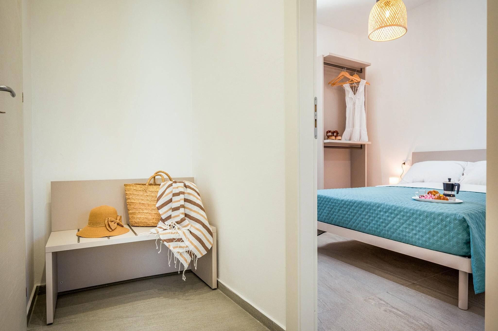 Ein Hotelzimmer mit einem Bett, einer Bank mit Hut und Tasche sowie einer Hängelampe.