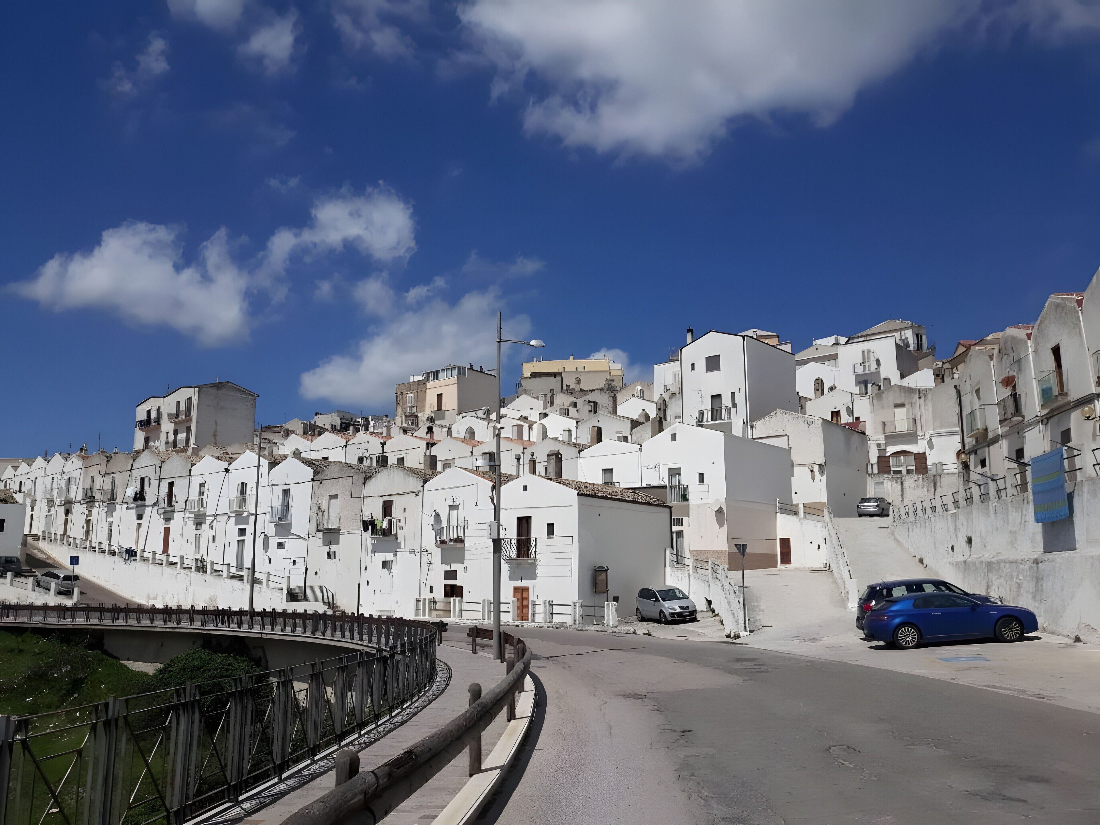 A coastal town with white buildings, a bridge, and a clear blue sky.