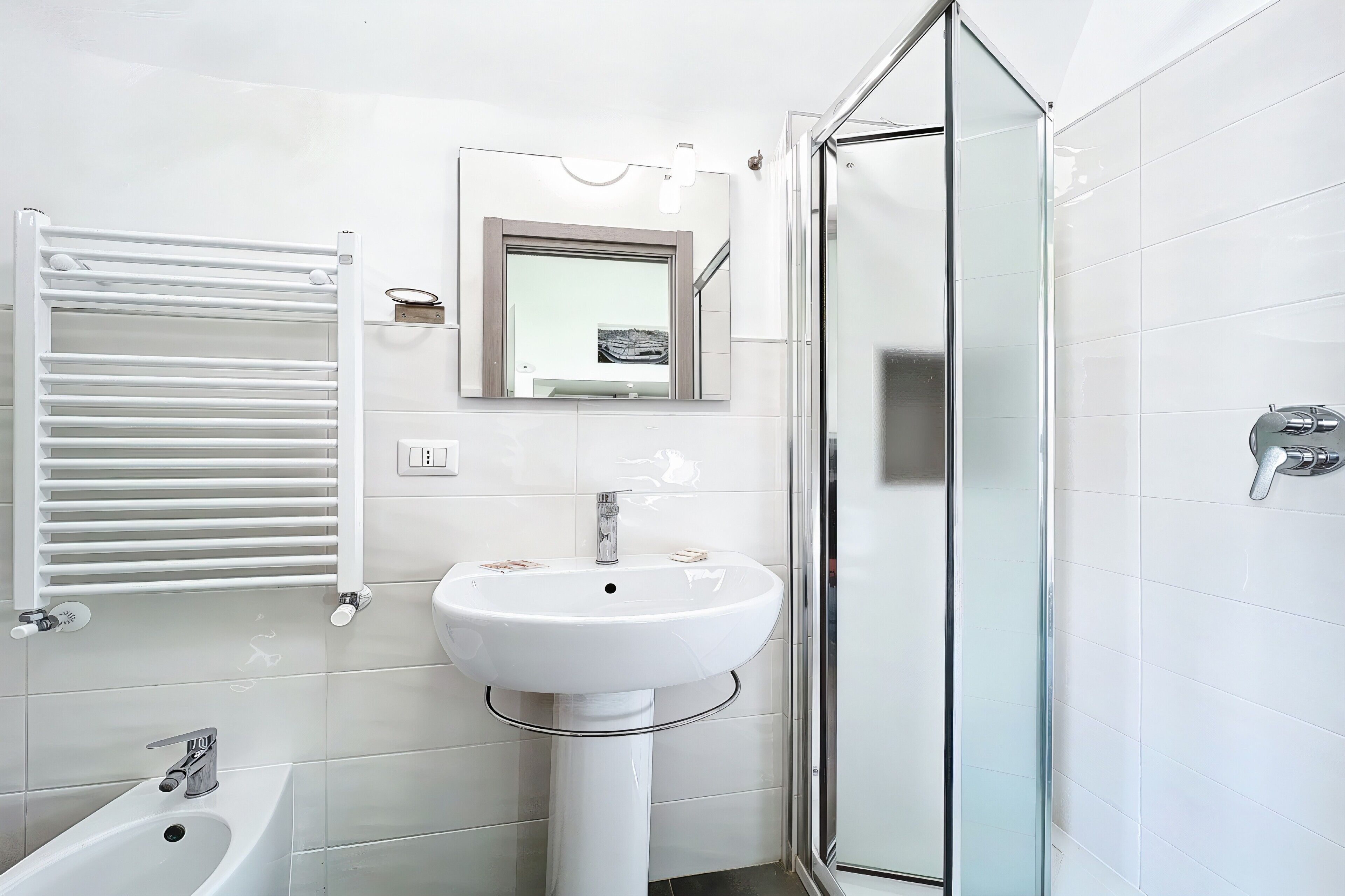 Une salle de bain avec un lavabo blanc, une cabine de douche en verre et un porte-serviettes.