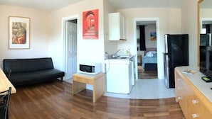 Een knus woongedeelte met een bank, een eettafel, een kitchenette en een klein keukenhoekje.