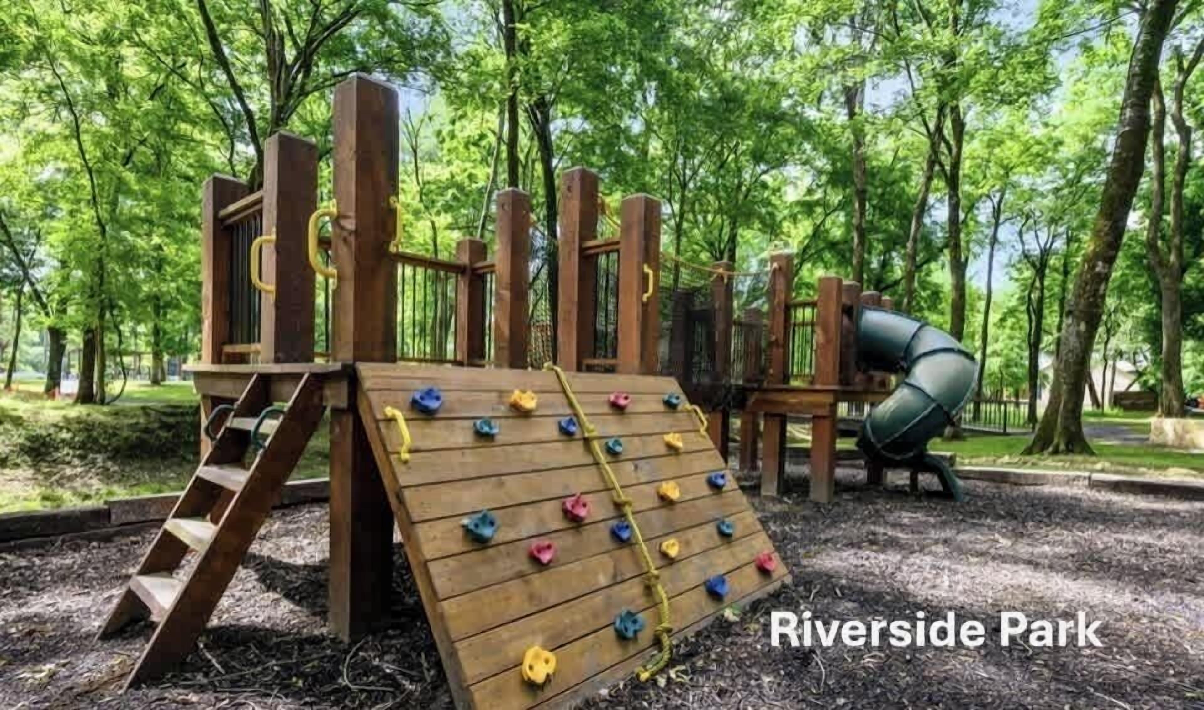 Ein Spielplatz mit einer hölzernen Kletterwand, einer Rutsche und einer Kletterleiter.