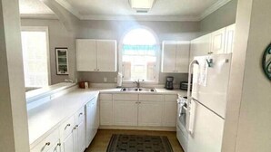 A narrow kitchen with white cabinets, a window, and a built-in oven. - 1st Floor Golf View Condo, Free Beach Shuttle, pool/ Hot Tub, Barefoot Landing (North Myrtle Beach)