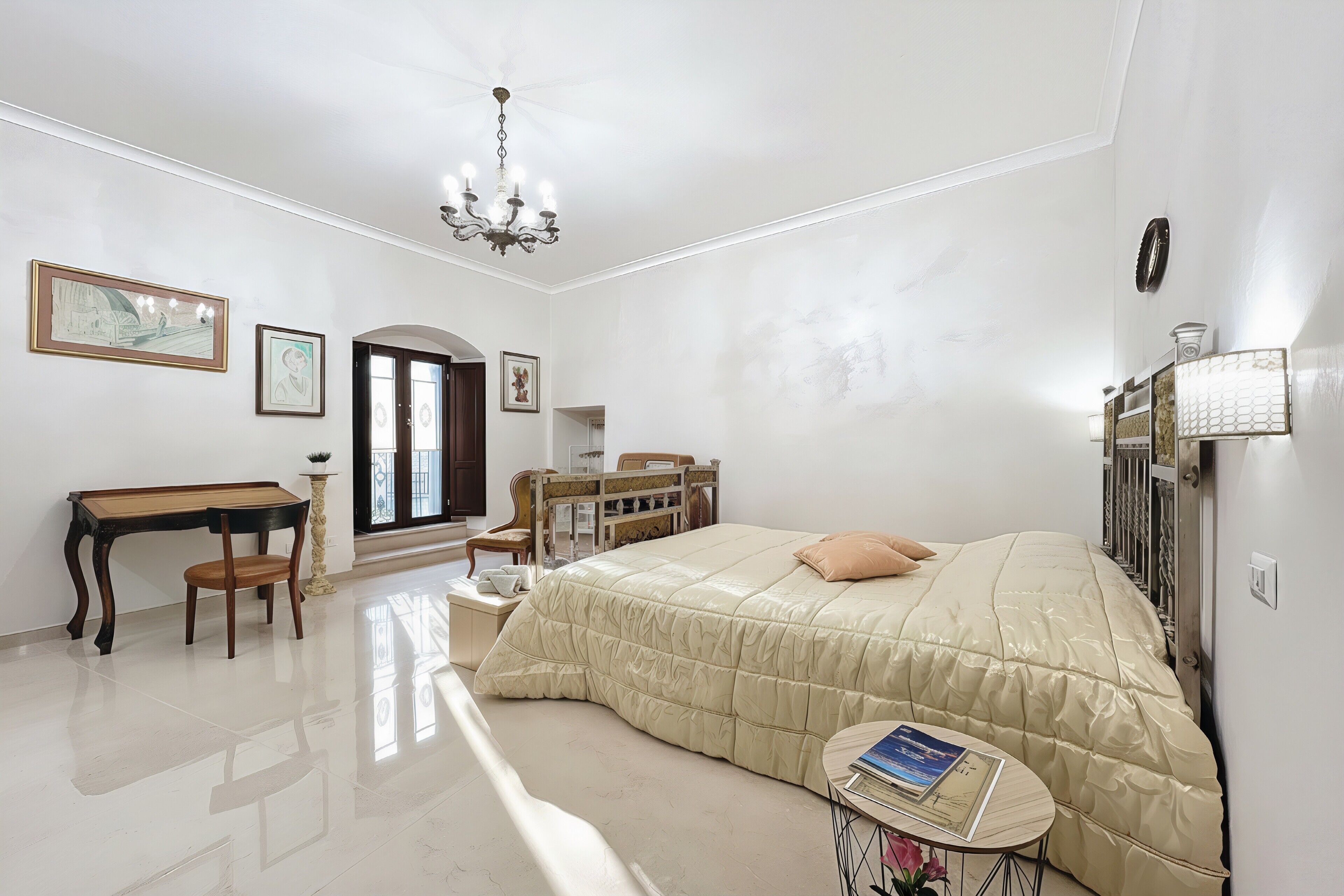 Una camera da letto con un letto, una scrivania, una sedia, un tavolino e un lampadario.