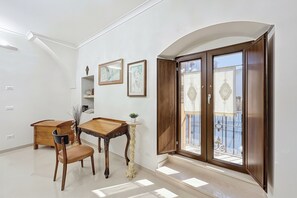 A room with a wooden dining table, a chair, a small plant, and a window with a view of the outside. - Mikiami Simply Welcoming (Monte Sant'Angelo)