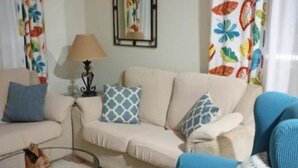 A living room with a beige sofa, a blue sofa, and a glass coffee table. - Holiday Home With Pool in Jerez (Jerez de la Frontera)