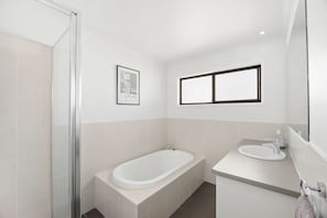 Ein modernes Badezimmer mit Duschkabine aus Glas, einer freistehenden Badewanne und einem Waschtisch.