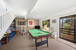 Ein Zimmer mit Billardtisch, Dartscheibe, gerahmtem Sporttrikot und Bücherregal.