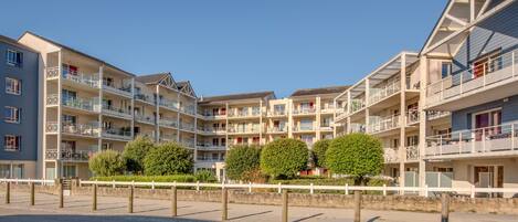 A multi-story hotel with balconies, a parking area, and a clear sky.
