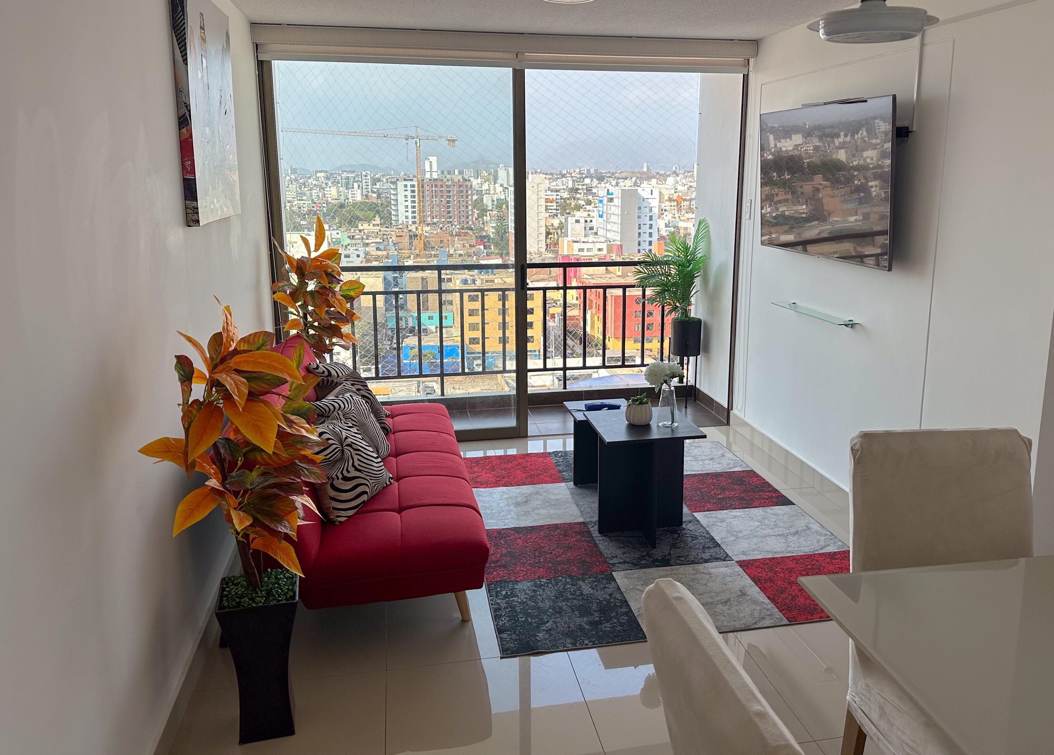 Ein modernes Wohnzimmer mit einem roten Sofa, einem Couchtisch und einem Balkon mit Blick auf die Stadt.