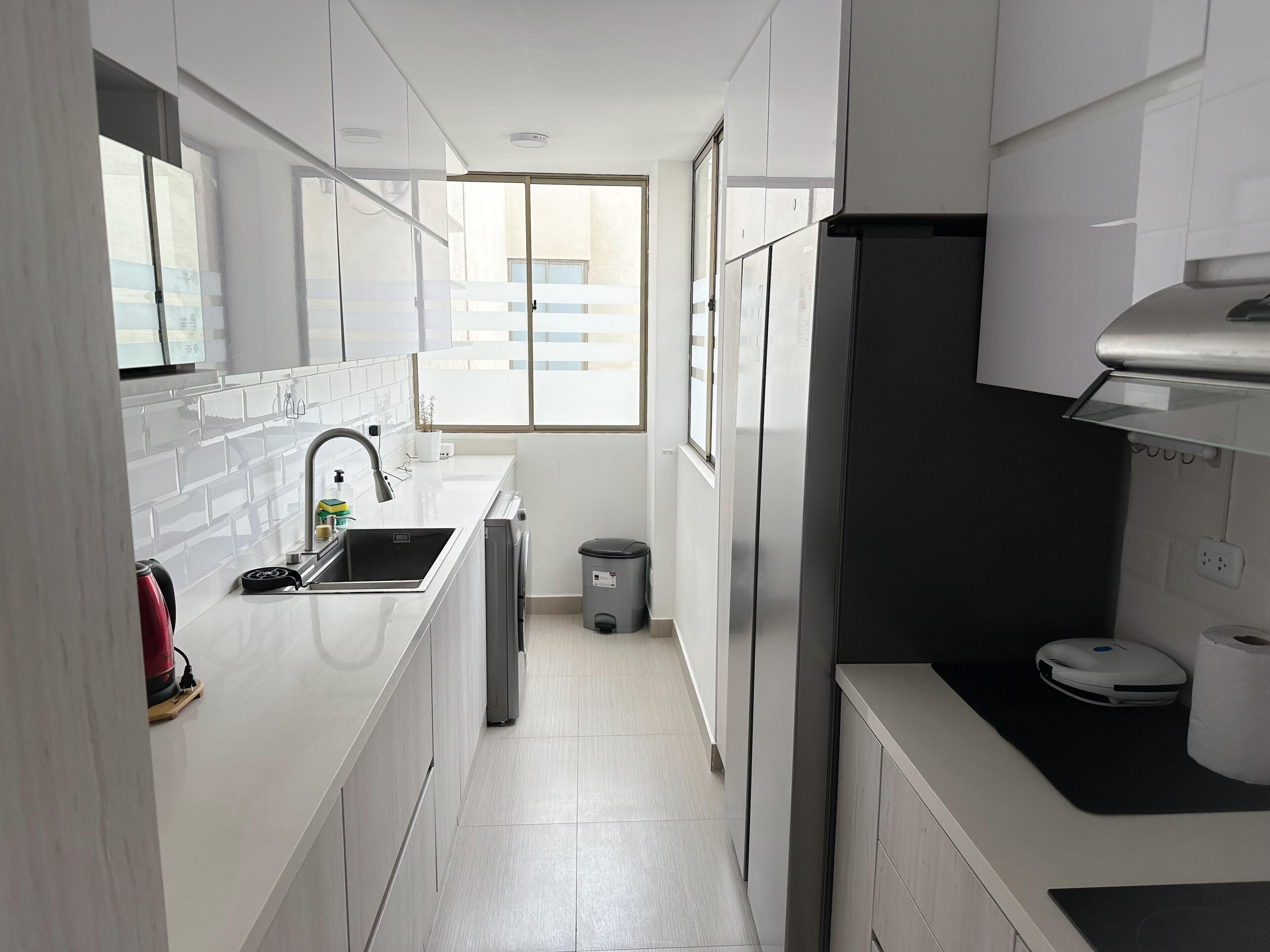 A modern kitchen with white cabinets, a stainless steel sink, and a black countertop.