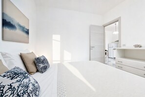 Un dormitorio moderno con cama, mesitas de noche, cómoda, espejo y un cuadro en la pared.