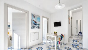A modern interior with a dining area, a painting, and a TV on the wall. - Apartment 'Le Case Di Chri' with Wi-Fi and Air Conditioning (Mattinata)