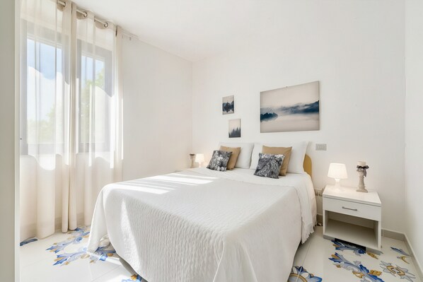 Un dormitorio con cama, mesitas de noche y decoración en la pared.