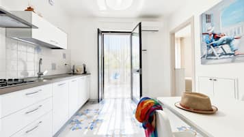 Una cocina moderna con armarios blancos, salpicadero de azulejos y vistas a través de un ventanal.