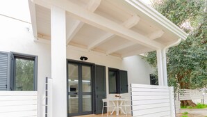 A covered outdoor area with a table and chairs, a sliding glass door, and a white exterior wall. - Apartment 'Le Case Di Chri' with Wi-Fi and Air Conditioning (Mattinata)
