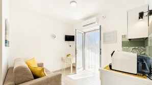 A modern living room with a sofa, a flat-screen TV, a dining area with a table and chairs, and a kitchen area with a toaster. - Apartment 'Le Case Di Chri' with Wi-Fi and Air Conditioning (Mattinata)