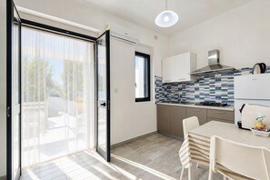 Une cuisine moderne dotée d’une porte-fenêtre coulissante, d’une cuisinière à gaz et d’un coin repas avec une table et des chaises.