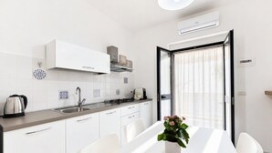 Una cocina moderna con armarios blancos, un hervidor de acero inoxidable y una mesa de comedor con sillas.