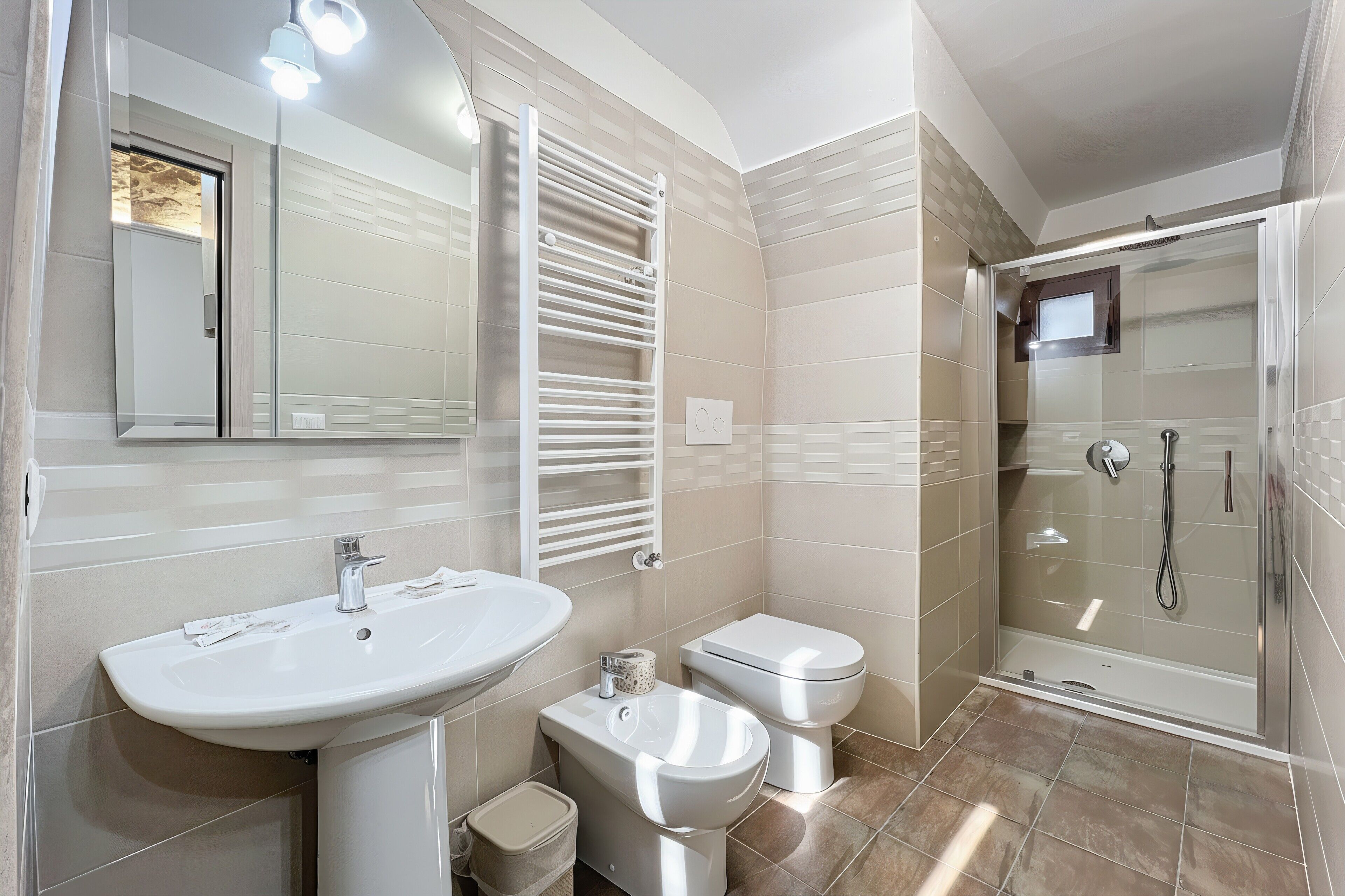 A modern bathroom with a sink, toilet, bidet, and a glass-enclosed shower.