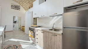 Een moderne keuken met een roestvrijstalen koelkast, houten kastjes, een ingebouwde oven en een groot raam voor natuurlijk licht.
