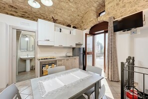 Une cuisine avec des meubles blancs, un évier, une cuisinière et une table à manger avec des chaises.