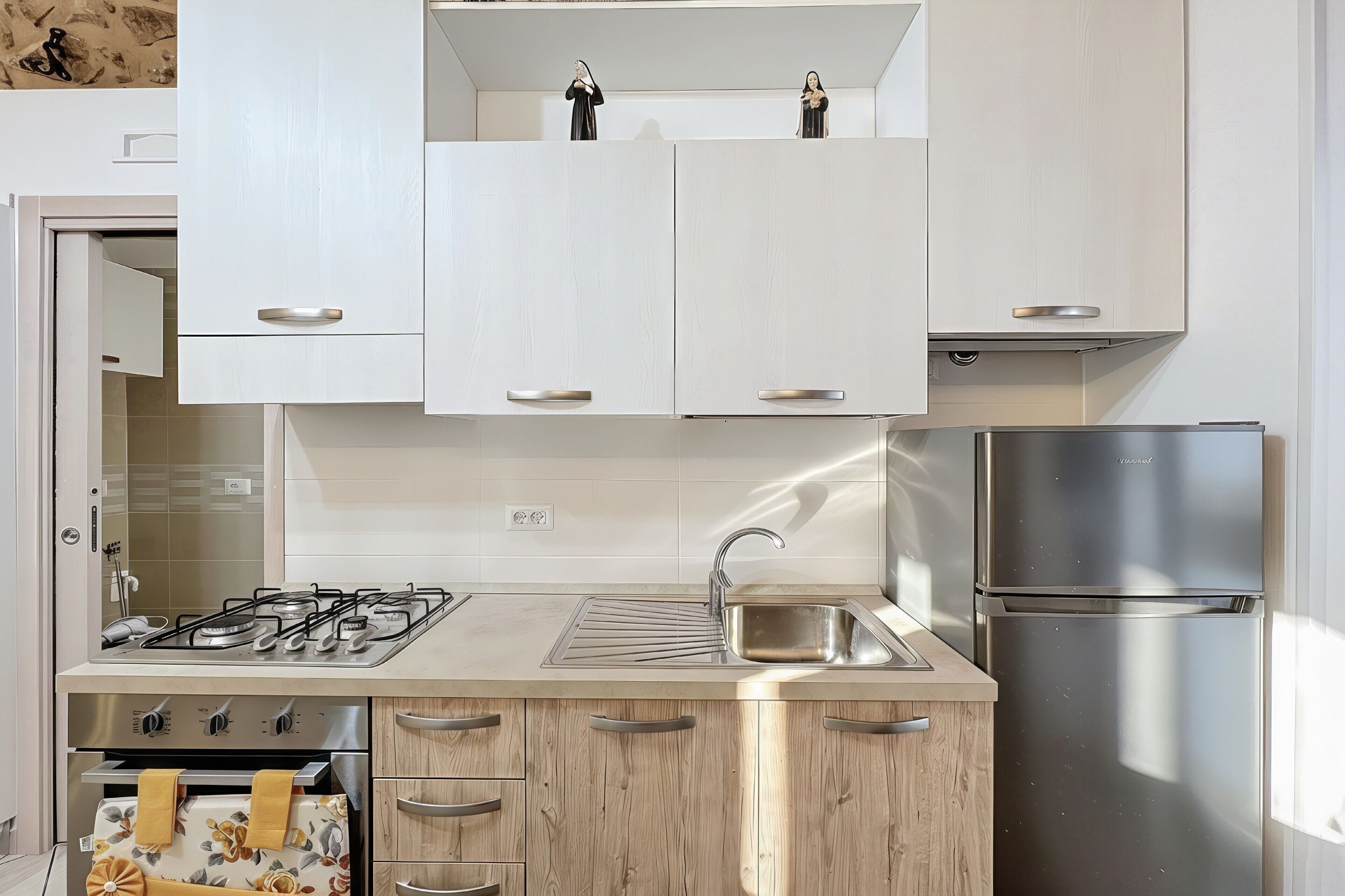 Eine moderne Küche mit weißen Schränken, einem Edelstahlkühlschrank, einem Gasherd und einer Spüle.