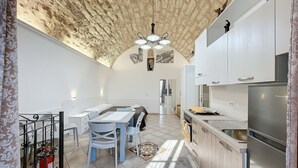 Een moderne keuken met een inbouwkoelkast, een eethoek met een tafel en stoelen, en een stenen plafond.