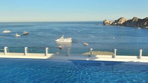 Una piscina con acqua cristallina, una costa rocciosa e diverse imbarcazioni in lontananza.
