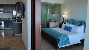 Una camera d'albergo con un letto, un comodino e vista sulla cucina.