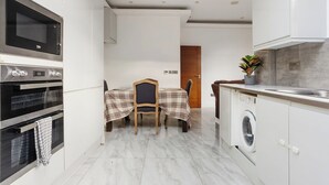 A modern kitchen with a microwave, oven, and washing machine. - 5 BR Flat |Spacious|Near Shepherd's Bush Stn.|ST (Greater London)