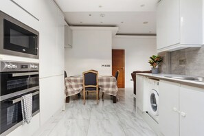 A modern kitchen with a microwave, oven, and washing machine. - 5 BR Flat |Spacious|Near Shepherd's Bush Stn.|ST (Greater London)