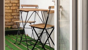 A room with a white wall, a window, and a door. There is a small table and two chairs outside the door. - 5 BR Flat |Spacious|Near Shepherd's Bush Stn.|ST (Greater London)