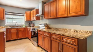 Una cocina con armarios de madera, encimeras de granito, horno de acero inoxidable y ventana con vistas.