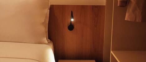 A hotel room with a bed, a bedside table, and a wall-mounted light fixture.