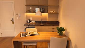 A modern kitchen with a dining area, including a wooden table, chairs, and a potted plant.